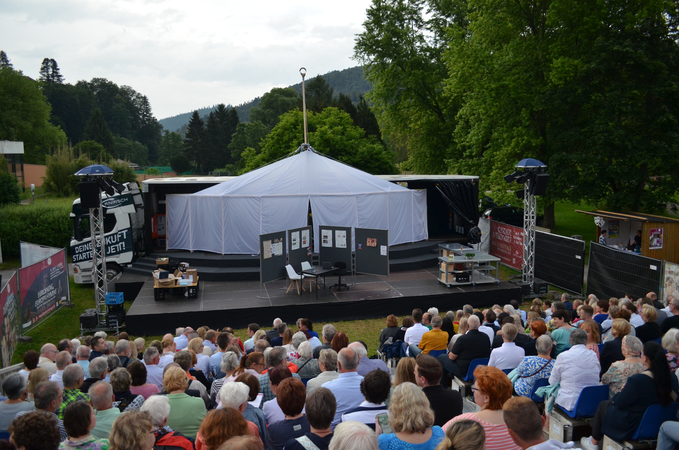 Menschen auf der Tribüne vor einer Theaterbühne