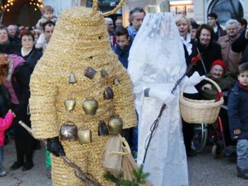 Zwei Personen, verkleidet in auffälligen, traditionellen Kostümen als Christkind und Pelzmärtle, sind umgeben von einer Menschenmenge,